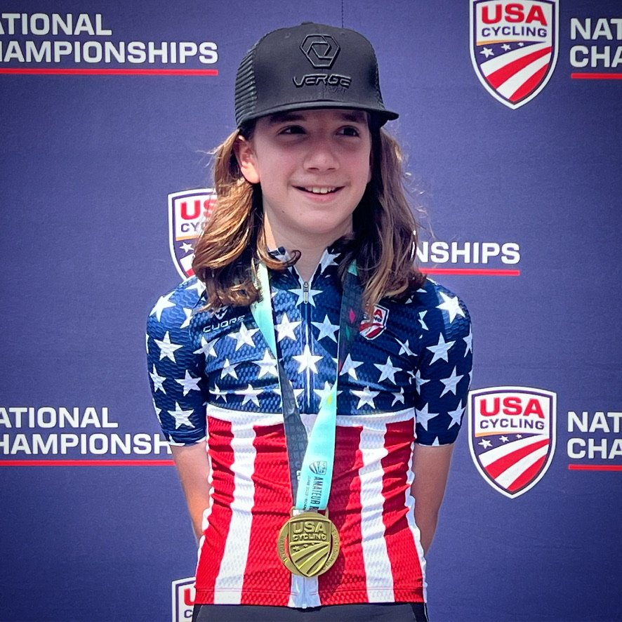 Athlete wearing a medal in front of a USA Cycling championship backdrop